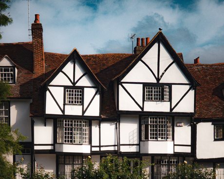 Two gabled houses with black-and-white timbered upper storeys, leaded windows, clay tiled roofs and brick chimney stacks.